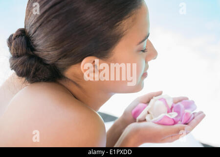 Sorridente brunette giacente su asciugamano tenendo i petali di rose Foto Stock