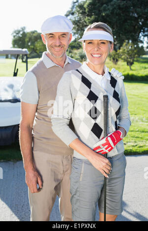 Felice golf giovane guardando la fotocamera con golf buggy dietro Foto Stock