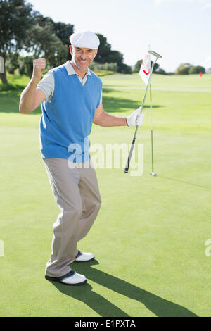 Felice golfista a fare il tifo per il putting green presso la diciottesima buca Foto Stock