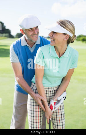 Golf giovane mettendo insieme a sfera sorridente alla telecamera ogni altro Foto Stock