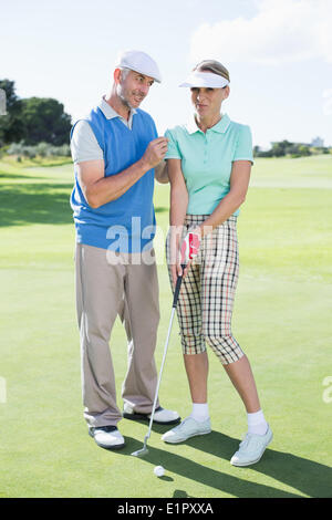 L'uomo coaching il suo partner sul putting green Foto Stock