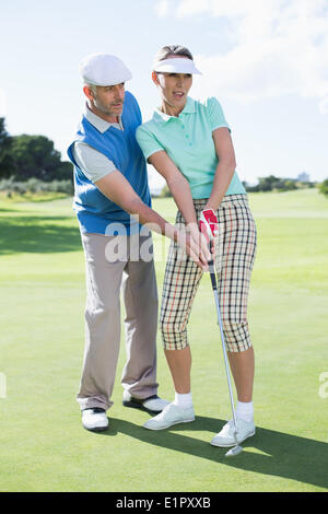 L'uomo coaching il suo partner sul putting green Foto Stock