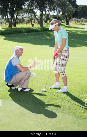 L'uomo coaching il suo partner sul putting green Foto Stock