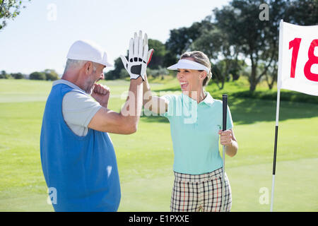 Golf giovane alta fiving sul campo da golf al diciottesimo foro Foto Stock