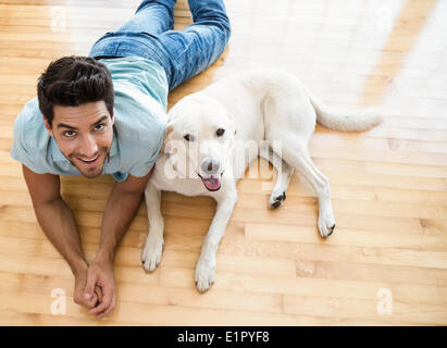 Attraente uomo disteso sul pavimento con la sua labrador Foto Stock