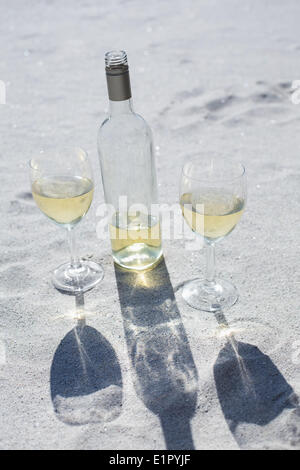 Vino bianco bottiglia e bicchieri sulla sabbia Foto Stock