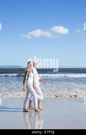 Coppia felice passeggiando a piedi nudi sulla spiaggia Foto Stock