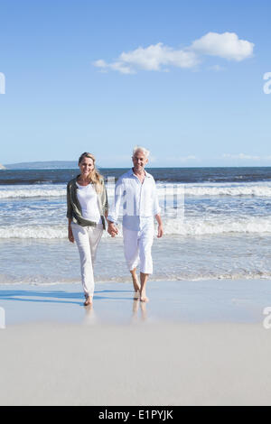 Coppia felice passeggiando a piedi nudi sulla spiaggia Foto Stock