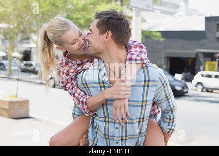 Giovane Hip uomo dando la sua ragazza bionda una piggy back Foto Stock