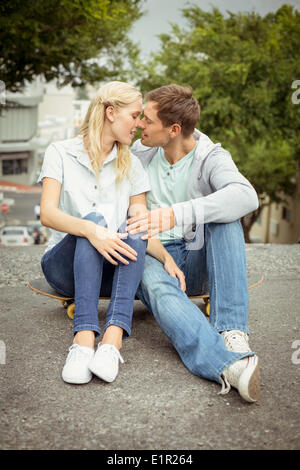 Hip coppia giovane seduto su skateboard kissing Foto Stock