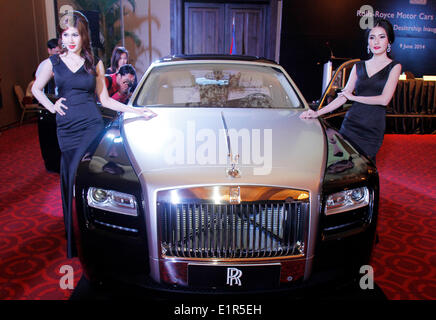 Phnom Penh. Il 9 giugno, 2014. I modelli rappresentano per fotografie con una Rolls-Royce auto il 9 giugno, 2014, in Phnom Penh Cambogia. Rolls-Royce automobili, uno del British iconica marche di auto, lunedì ha lanciato ufficialmente la sua prima concessionaria in Cambogia a toccare nel paese la crescente domanda di automobili di lusso. Credito: Sovannara/Xinhua/Alamy Live News Foto Stock