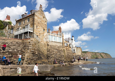 Le persone che si godono il sole a Robin Hood's Bay Yorkshire England Regno Unito Foto Stock
