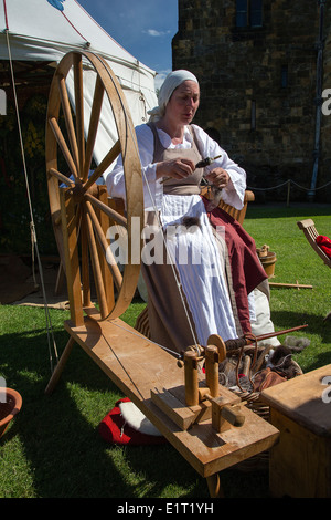 Donna in abiti tradizionali la filatura della lana su una vecchia ruota di filatura a Alnwick Castle, dove Harry Potter è stato girato. Foto Stock