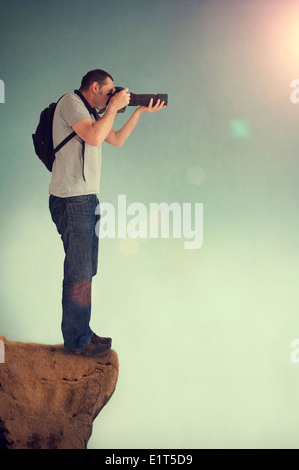 Fotografo in una montagna di scatti da un alto punto di vantaggio con una fotocamera reflex Foto Stock