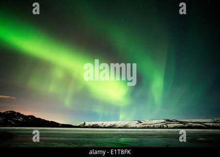 Le luci del nord brillano al di sopra di un lago ghiacciato al di fuori di Reykjavik in Islanda Foto Stock