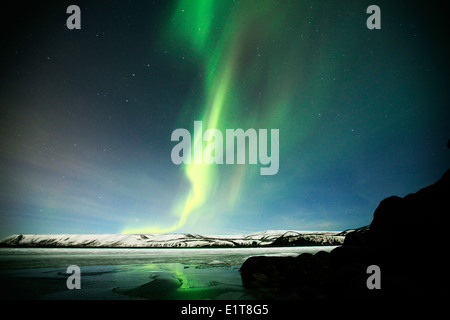 Le luci del nord brillano al di sopra di un lago ghiacciato al di fuori di Reykjavik in Islanda Foto Stock