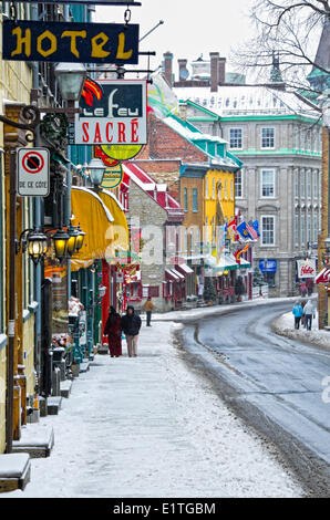 I turisti a piedi su una vecchia strada con il patrimonio di edifici commerciali nella parte vecchia di Quebec City in inverno durante una nevicata, Quebec, Cana Foto Stock