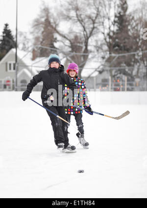 Ragazzi giocare hockey su ghiaccio, su un quartiere outdoor rink, Winnipeg, Manitoba, Canada Foto Stock