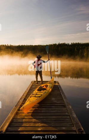 L'uomo sul dock con kayak, poco Deer Lake, Lac La Ronge Parco Provinciale, Northern Saskatchewan, Canada Foto Stock