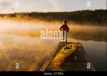 L'uomo sul dock con kayak, poco Deer Lake, Lac La Ronge Parco Provinciale, Northern Saskatchewan, Canada Foto Stock