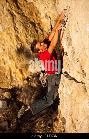 Un uomo si arrampica il percorso dello sport il fuoco nel cielo 12b al tramonto, Echo Canyon, Canmore, Alberta, Canada Foto Stock