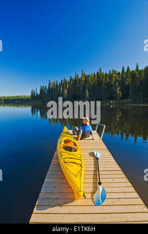 Uomo con kayak sul dock, appeso cuore laghi, Prince Albert National Park, Saskatchewan, Canada Foto Stock
