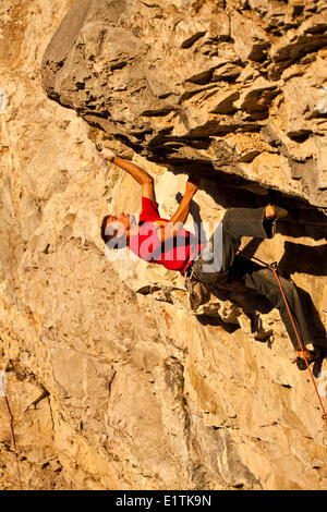 Un uomo si arrampica il percorso dello sport il fuoco nel cielo 12b al tramonto, Echo Canyon, Canmore, Alberta, Canada Foto Stock