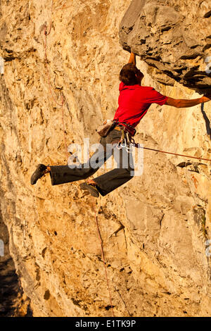 Un uomo si arrampica il percorso dello sport il fuoco nel cielo 12b al tramonto, Echo Canyon, Canmore, Alberta, Canada Foto Stock