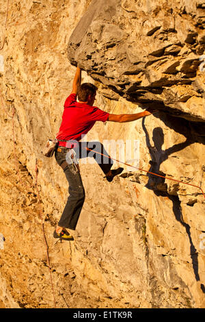 Un uomo si arrampica il percorso dello sport il fuoco nel cielo 12b al tramonto, Echo Canyon, Canmore, Alberta, Canada Foto Stock