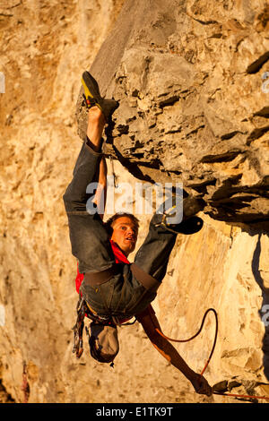 Un uomo si arrampica il percorso dello sport il fuoco nel cielo 12b al tramonto, Echo Canyon, Canmore, Alberta, Canada Foto Stock