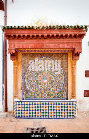Decorativo tradizionale fontanella su un calce-lavato via stretta all'interno della Medina di Rabat, Marocco. Foto Stock