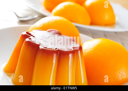 Ingrandimento di una piastra con creme caramel e pesche sciroppate su un set table Foto Stock