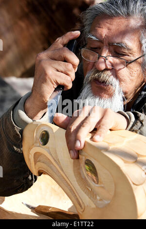 Una delle prime nazioni carver che lavora su un pezzo di Eagle, scolpite da giallo cedro, Tofino, Isola di Vancouver, British Columbia, Canada Foto Stock