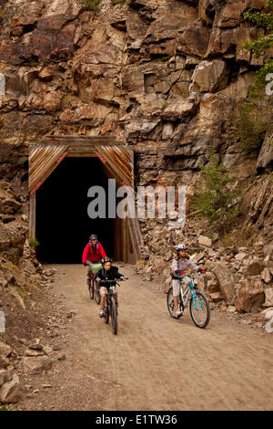 Famiglia giovane in bicicletta il Kettle Valley Railway Trail attraverso Myra canyon, Okanagan Valley, BC, Canada. Foto Stock