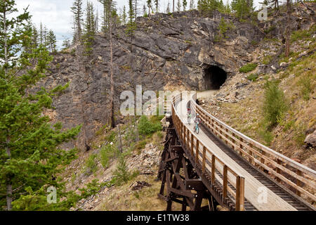 Famiglia giovane in bicicletta il Kettle Valley Railway Trail attraverso Myra canyon, Okanagan Valley, BC, Canada. Foto Stock