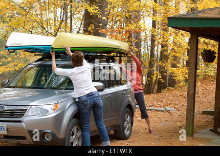 Due giovani donne kayaks di carico sul tetto del veicolo al cottage vicino al lago Oxtongue, Muskoka, Ontario, Canada. Foto Stock