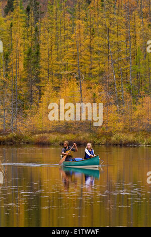 Coppia giovane paddle canoa sul ancora acqua di ruscello nel nordovest della fine del Algonquin Park, Ontario, Canada. Foto Stock