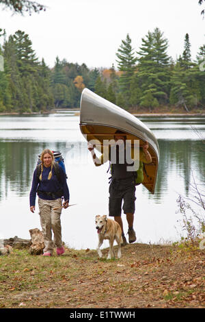 Coppia giovane portage canoa da piccolo lago nel nordovest della fine del Algonquin Park, Ontario, Canada. Foto Stock