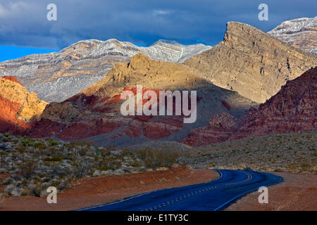 Paese strada che conduce verso la coperta di neve di primavera Montagne vicino al Red Rock Canyon National Conservation Area vicino a Las Vegas Foto Stock