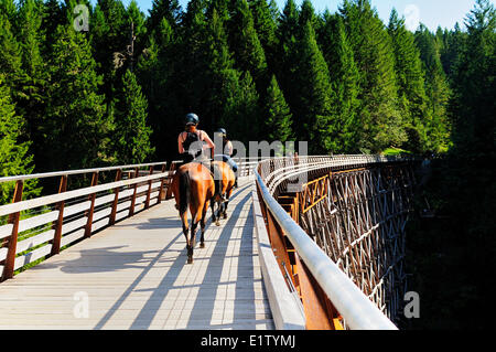 Due donne su cavalli corsa oltre il recentemente rinnovato Kinsol traliccio in Lago di Shawnigan, BC. Foto Stock