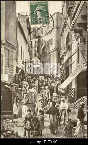 Questa fotografia dell'inizio del XX secolo scattata da Algeri cattura una vivace strada nella Casbah, un quartiere storico della città. L'immagine fornisce informazioni sul paesaggio urbano e sulla vita quotidiana di Algeri nel 1909. Foto Stock