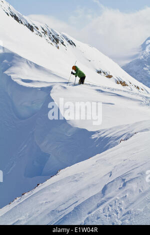 Un maschio di backcountry rider il taglio di un cornicione di fare alcune prove di pendenza prima di impegnare la linea di sci. Ghiacciaio Lodge, Golden, BC Foto Stock