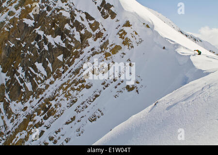 Un maschio di backcountry rider il taglio di un cornicione di fare alcune prove di pendenza prima di impegnare la linea di sci. Ghiacciaio Lodge, Golden, BC Foto Stock