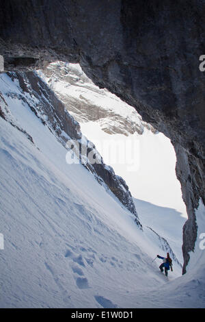 Un maschio di backcountry rider bootpacks su una ripida couloir con un unico arco calcareo in esso. Mt. Il francese Peter Lougheed provinciale Foto Stock