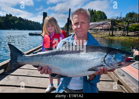 Orgoglioso pescatore con 24 libbre di Salmone Chinook e indifferente figlia. Foto Stock