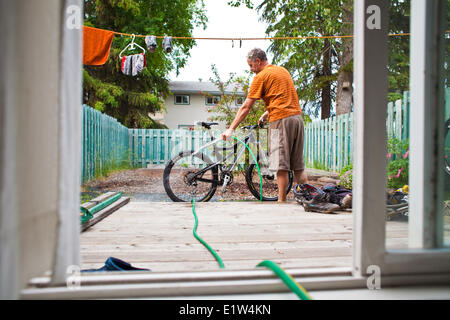 Un uomo di mezza età il lavaggio in giù la sua mountain bike dopo un giro fangoso in Golden, BC Foto Stock