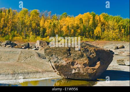 Roccia irregolare precambrian shield roccia lungo il fiume Winnipeg con colori autunnali in background nei pressi di sette sorelle Manitoba Foto Stock