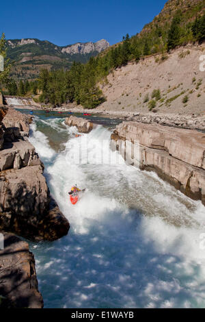 Un maschio di kayaker corre l'impegnativo della parte superiore Elk River, Fernie, BC Foto Stock