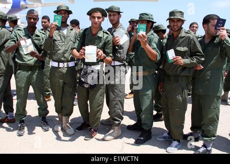 Tripoli, Libia. Decimo Giugno, 2014. Soldati posano per le foto con i loro passaporti prima di salire a bordo di un aereo in Mitiga aeroporto di Tripoli, in Libia, il 10 giugno 2014. Un lotto di ribelli che hanno aderito alla Libia dell esercito regolare a sinistra per la Gran Bretagna di ricevere una formazione in Libia esercito-piano di ricostituzione. © Hamza Turkia/Xinhua/Alamy Live News Foto Stock