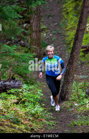 Una donna corre fino alla cima di una collina in i sentieri intorno al Lazo Marsh in Comox. Il Comox Comox Valley Vancouver Island British Columbia Foto Stock